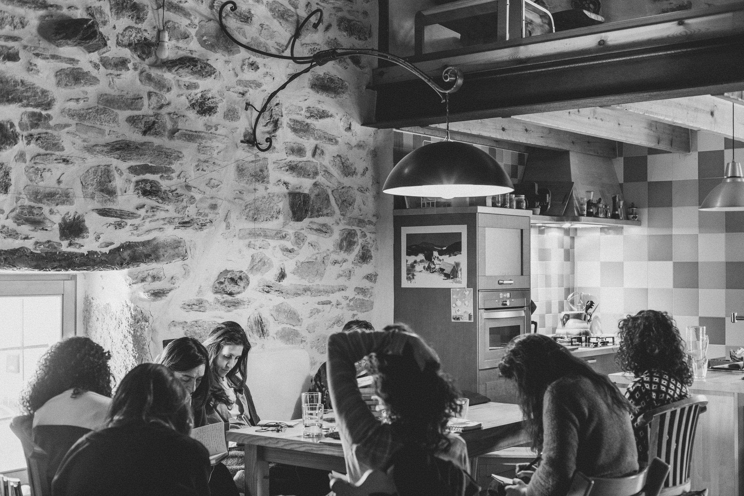 Lectura compartida en entorno rural | Arrinconados – Retahílo Ediciones grupo de mujeres leyendo juntas en mesa en casa rural encuentro literario en blanco y negro