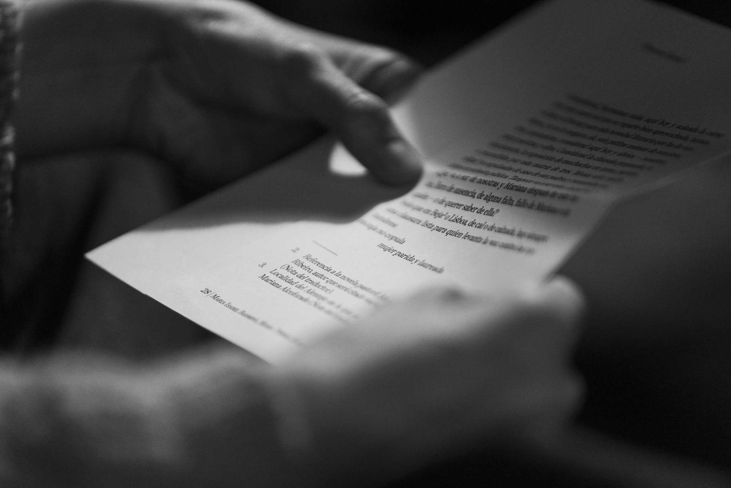 Lectura íntima de un libro en blanco y negro Manos sosteniendo un libro abierto mientras se lee en un entorno íntimo en blanco y negro