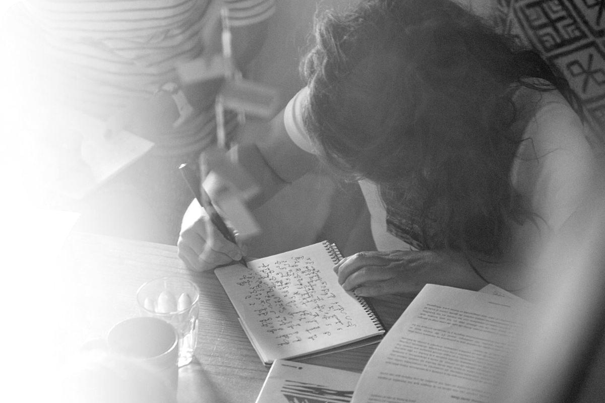 Persona escribiendo en un cuaderno durante un encuentro de escritura creativa