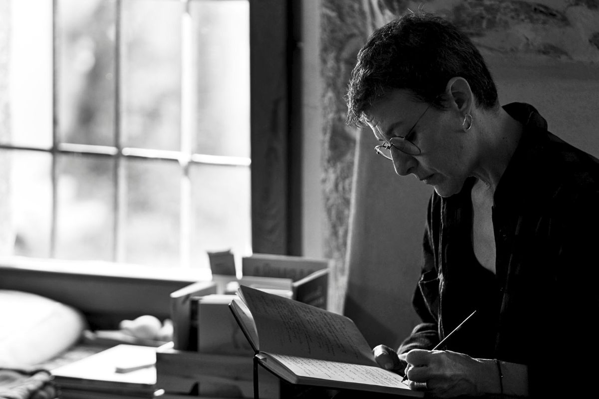 Diana Sánchez Lobato escribiendo en un cuaderno junto a una ventana con luz natural